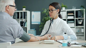 Doctor takes elderly patient's blood pressure.