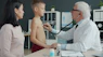 Doctor examines boy's chest with stethoscope while mother watches.