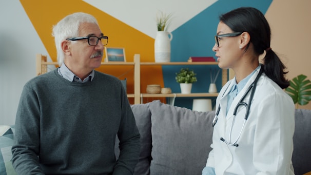 Doctor consults with an elderly patient on a couch.