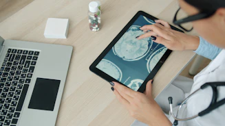 Doctor examining brain scan on tablet at desk.
