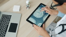 Doctor examining brain scan on tablet at desk.