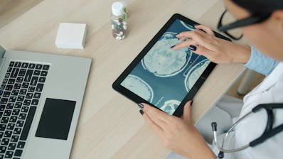 Doctor examining brain scan on tablet at desk.