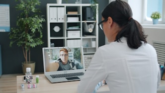 Doctor consulting patient via video call on laptop.