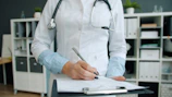 Doctor writing on clipboard in office