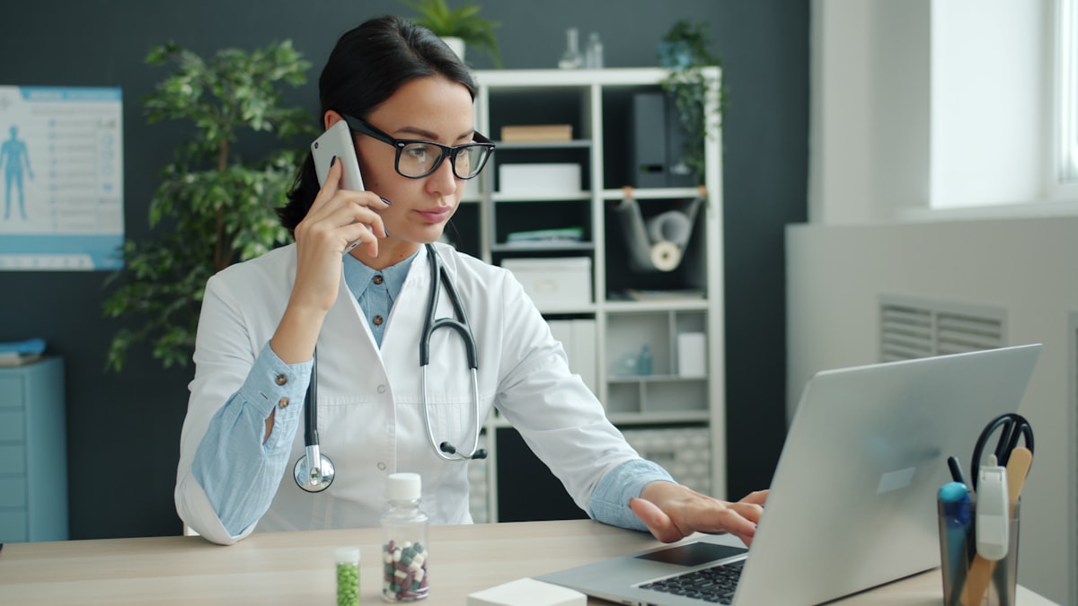 A clinician on the phone at her desk, answering a parent's question between visits