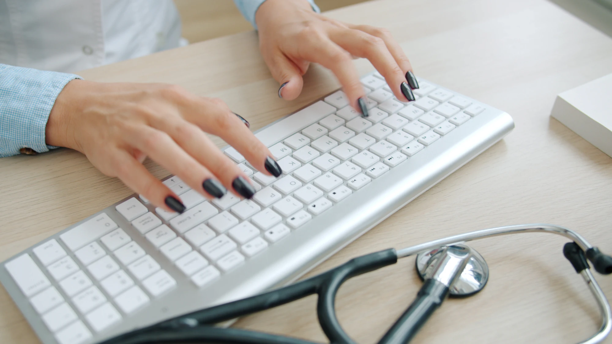 A doctor using a computer keyboard at a hospital desk
