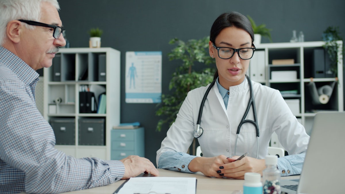 A clinician talking with a patient across a desk in a consultation room