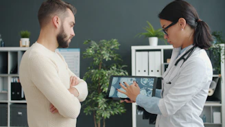 Doctor shows patient medical scan on tablet.