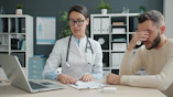 Doctor consults with a distressed male patient in office