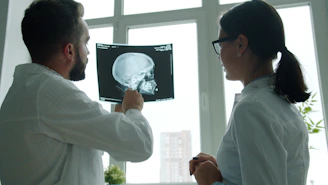 Two doctors examine a skull x-ray together.