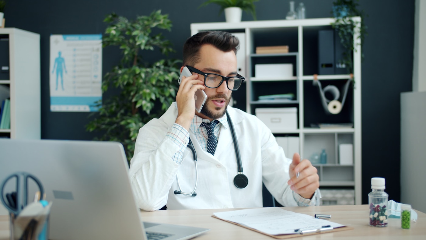 Médico hablando por teléfono en su consultorio