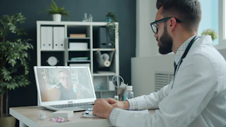 Doctor consulting patient via video call on laptop.
