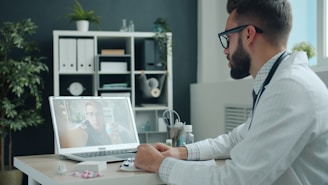 Doctor consulting patient via video call on laptop.