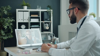 Doctor consulting patient via video call on laptop.