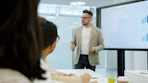 Man presenting data on a large screen to colleagues.