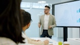 Man presenting data on a large screen to colleagues.