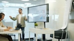Man presenting data on a large screen to colleagues.