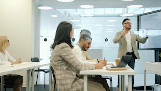 Man presenting to colleagues in a modern office meeting room.