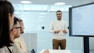 Man presents to colleagues in a modern office meeting.