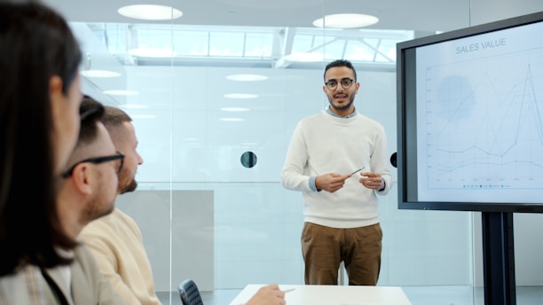Man presents to colleagues in a modern office meeting.