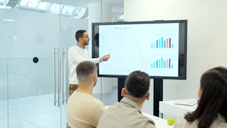Man presenting charts on a large screen to audience.