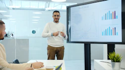 Man presents charts on a screen during a meeting.