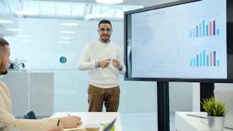 Man presents charts on a screen during a meeting.