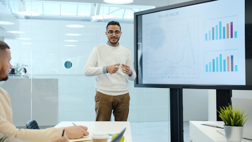 Man presents charts on a screen during a meeting.