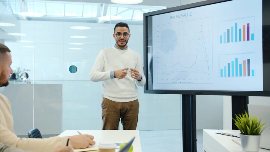 Team member presenting sales and growth charts on a screen to colleagues