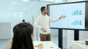Man presenting charts on a large screen.
