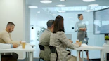 Woman presenting to colleagues in a modern office meeting.
