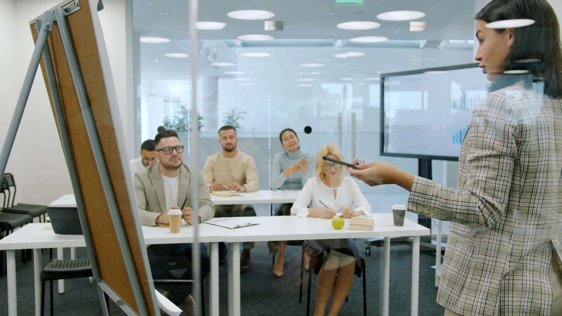 Woman presenting to a group in a modern office.