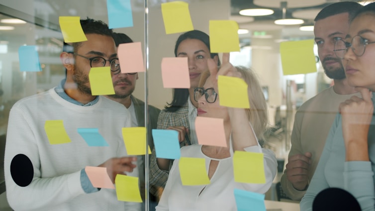 Team brainstorms using sticky notes on glass wall
