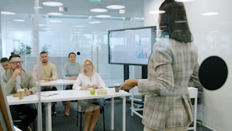 Woman presenting to an attentive audience in a modern office.