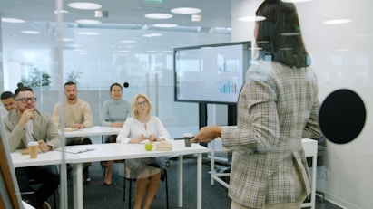 Woman presenting to an attentive audience in a modern office.