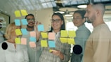 Team collaborating with sticky notes on glass wall
