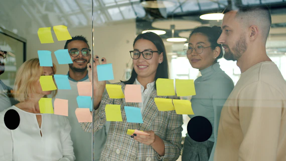 Team collaborating with sticky notes on glass wall