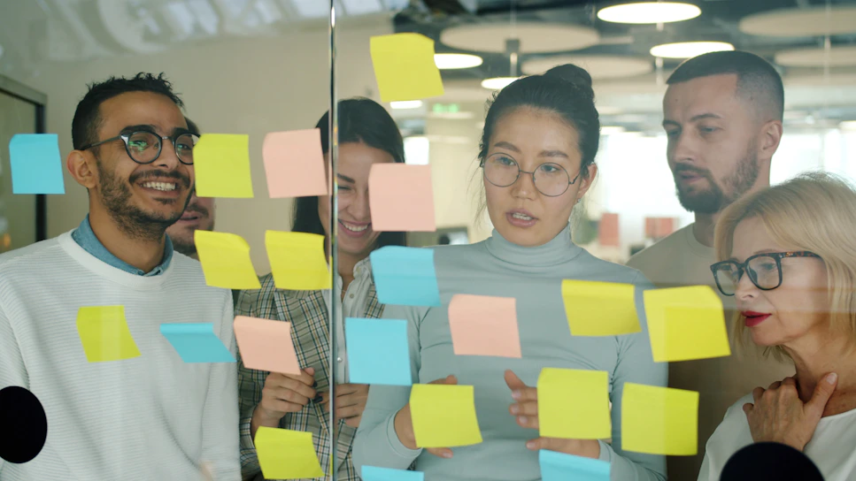Team brainstorming with colorful sticky notes on glass.