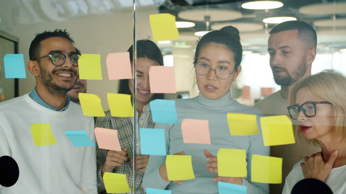 Tim merancang strategi pemasaran dengan sticky notes di kaca