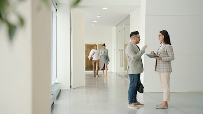 Two people talking in a modern office hallway.