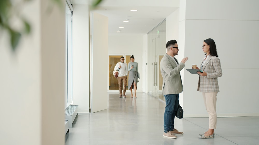 Two colleagues discussing an employee monitoring rollout while walking through a modern office hallway.