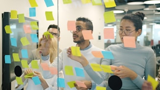 Team brainstorming ideas on a glass wall with sticky notes.