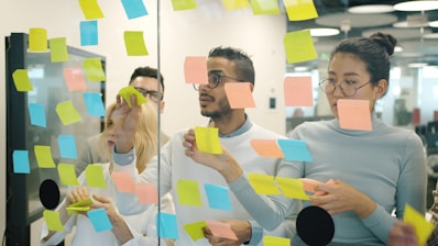 Team brainstorming ideas on a glass wall with sticky notes.