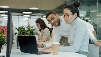 Two colleagues collaborating on a laptop in office.