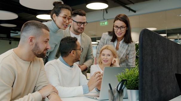 Diverse team collaborating around a laptop in office.