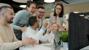 Diverse team celebrating success at office desk.