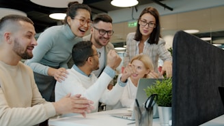 Diverse team celebrating success at office desk.