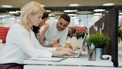 Three people working together on a laptop.