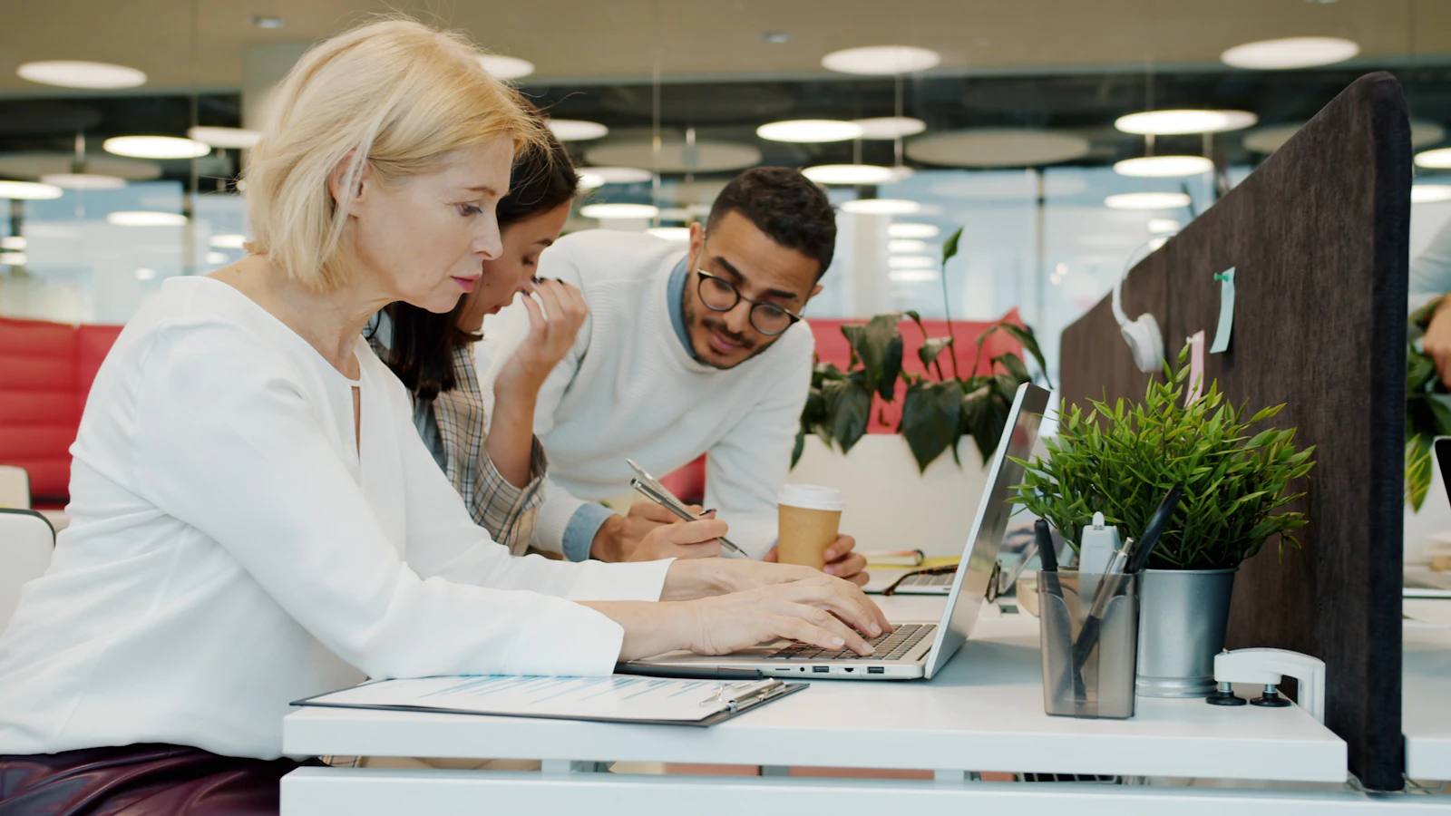 Three freelancers reviewing a project together on a laptop in a shared studio workspace