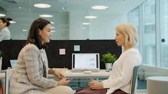 Two women talking in a modern office setting.